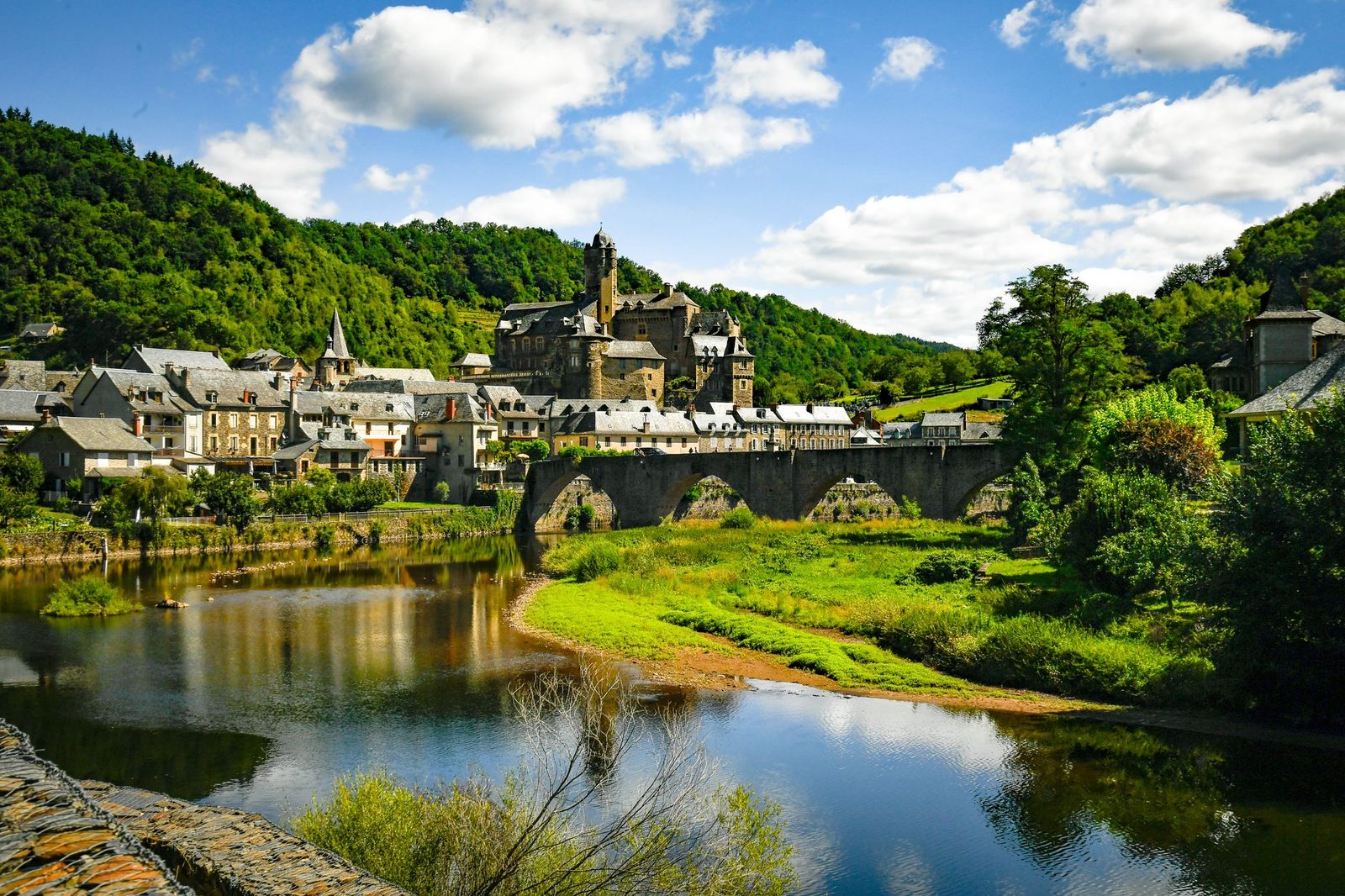 Explore the picturesque village of Estaing and its historic castle surrounded by lush greenery and a serene river.