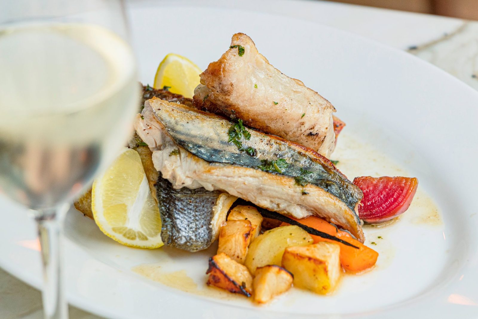 Savor this beautifully presented fish dish with roasted vegetables and a lemon garnish.
