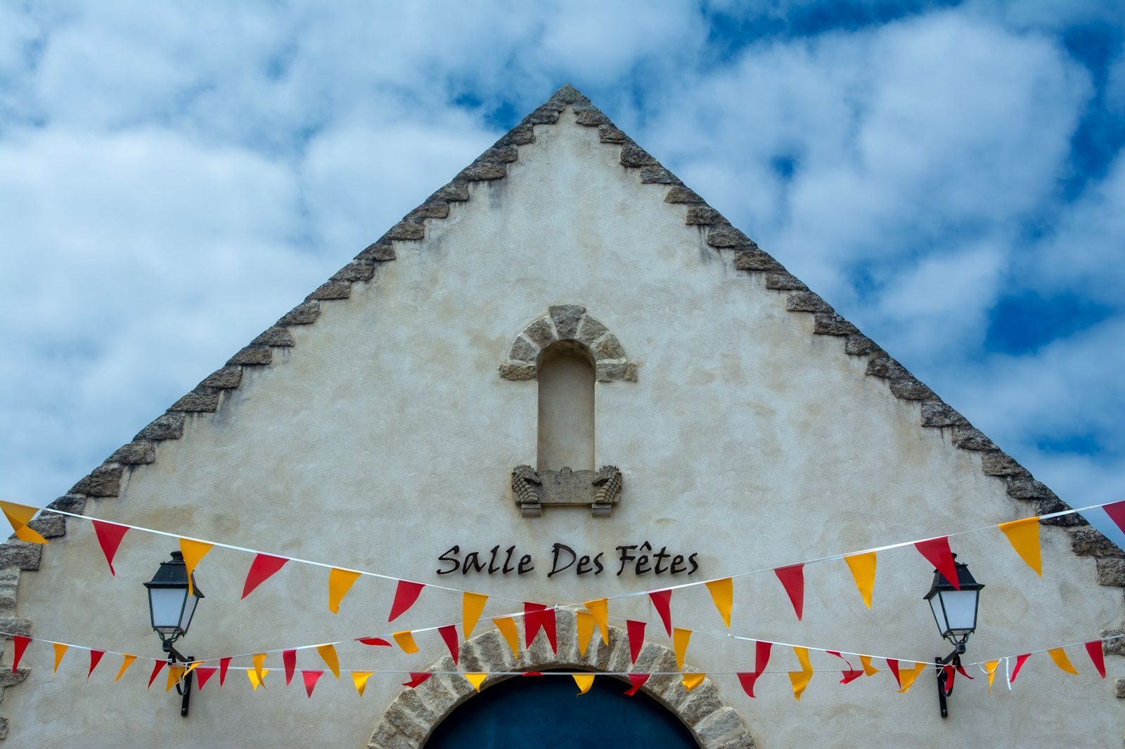 A picturesque village hall with festive bunting against a bright blue sky.