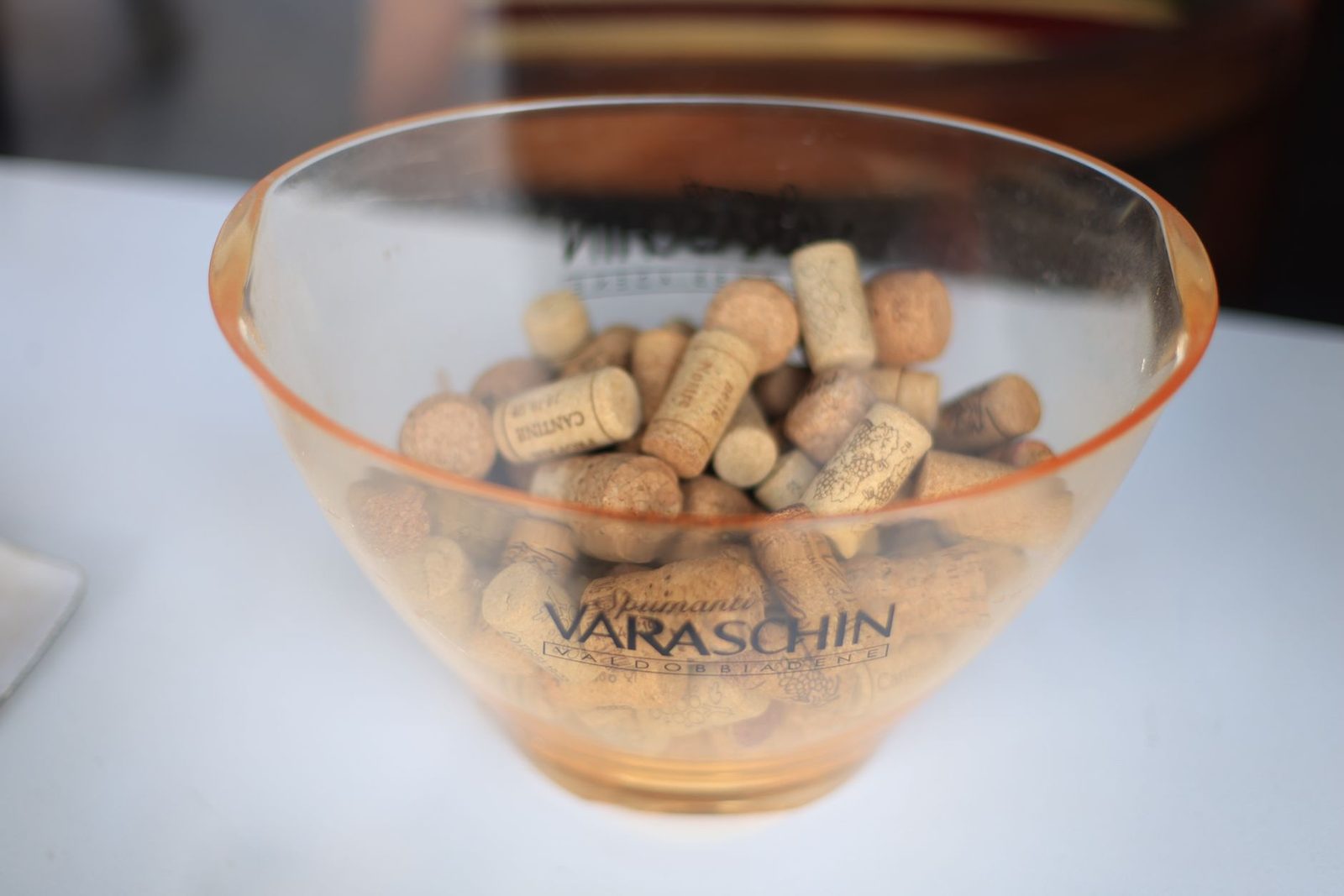Close-up of a Varaschin glass bowl containing assorted wine corks on a table.