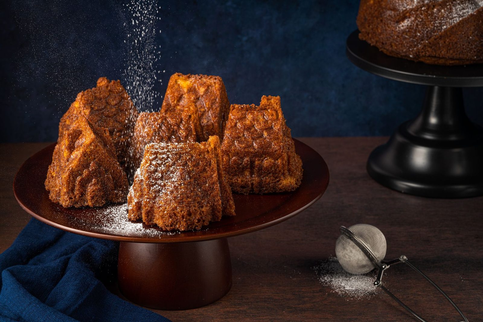 Aesthetic arrangement of rustic cakes sprinkled with powdered sugar on a wooden platter.