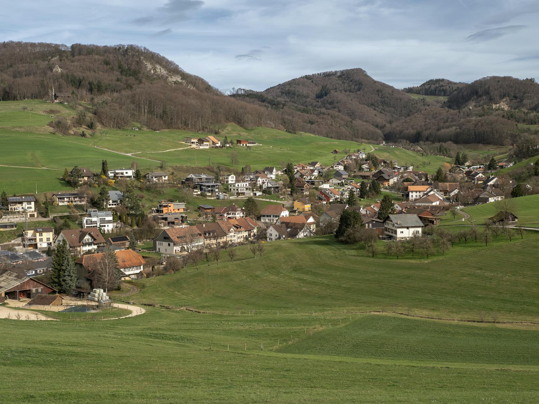 Charming Swiss village nestled in lush green hills with scenic mountain backdrop, perfect for travel inspiration.