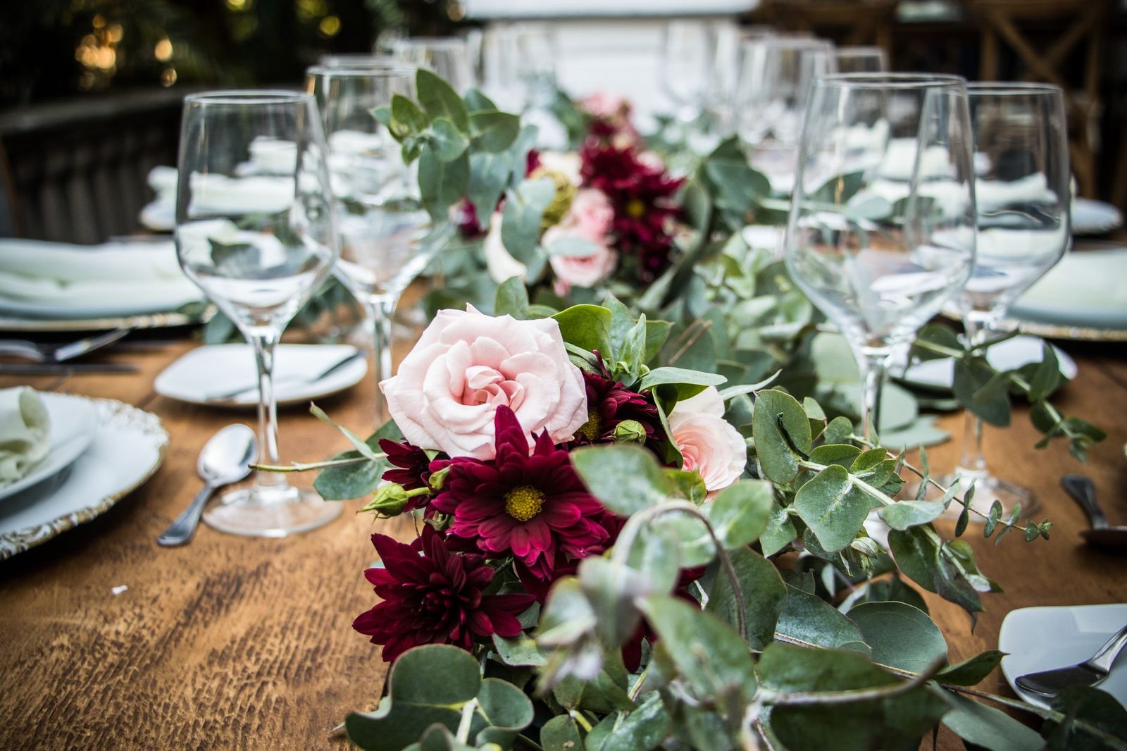 Beautiful floral arrangement with roses and eucalyptus on a set dining table, creating an elegant atmosphere.