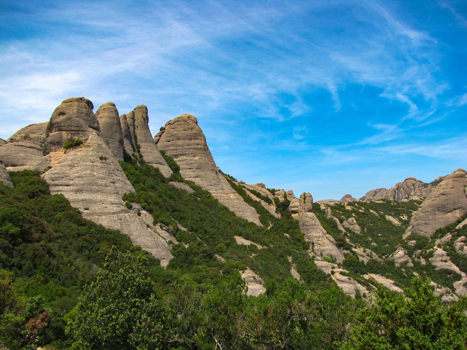 Panoramic view of Montserrat's unique rock formations against a bright blue sky.