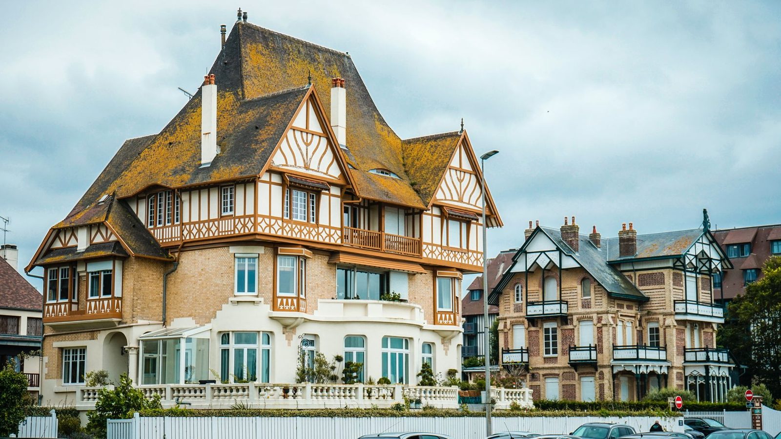 Elegant Tudor-style mansion set against a cloudy blue sky, showcasing architectural beauty.