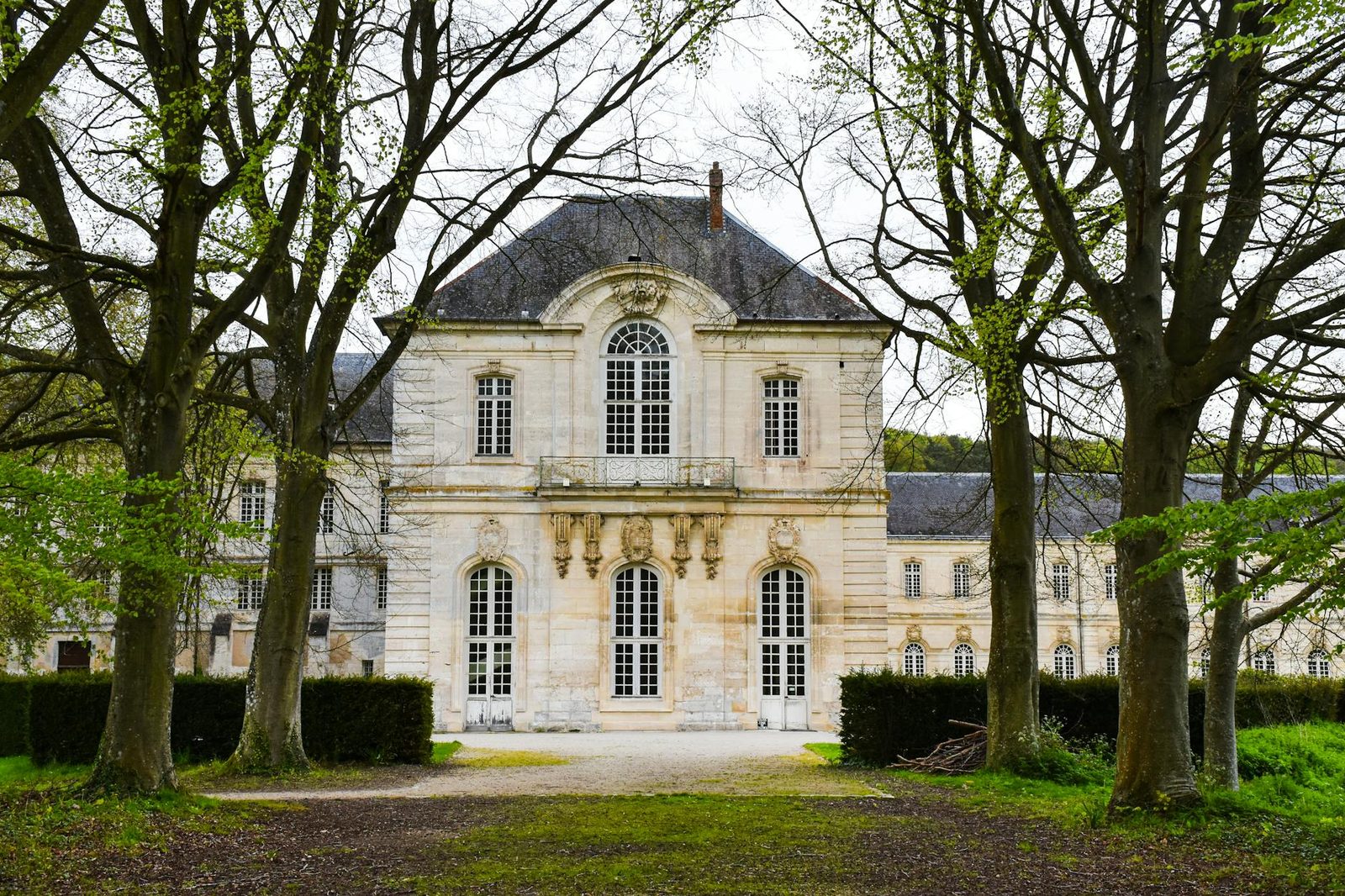 Elegant historic mansion with classical architecture, nestled among trees in France.