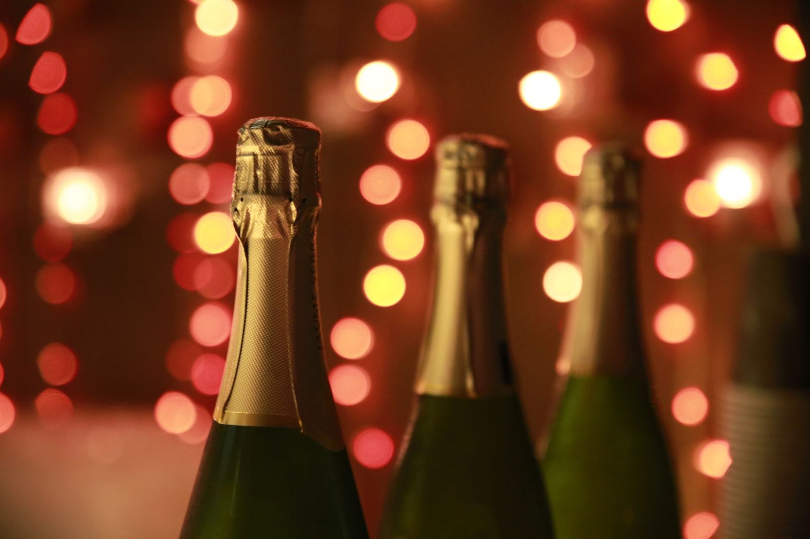 Champagne bottles in a warm festive setting with sparkling bokeh lights for celebration.
