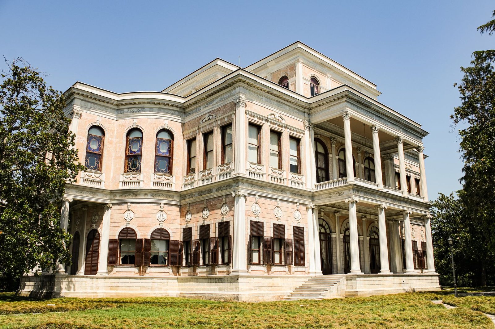 A grand historical mansion showcasing elegant architecture with classical columns during the daytime.