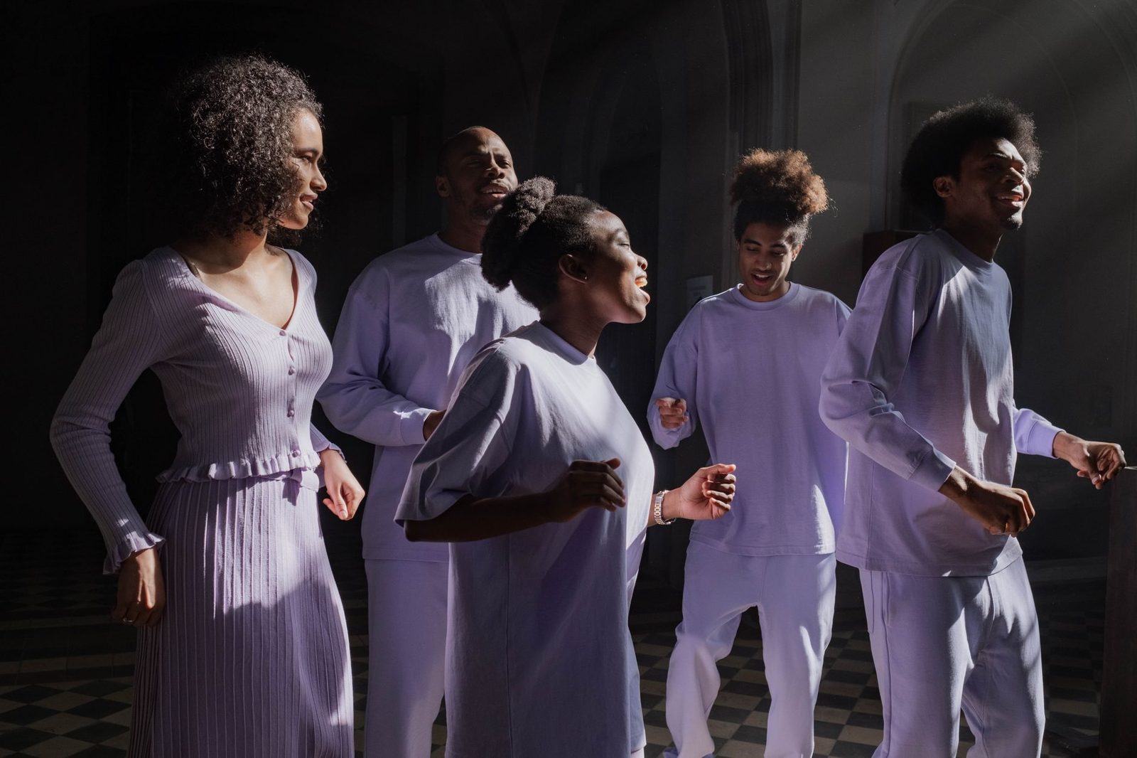 A group of diverse adults singing energetically inside a church with sunbeams streaming through.