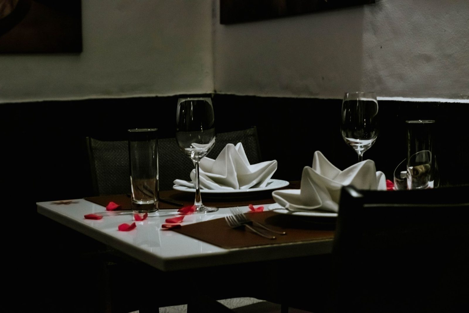 A romantically set dinner table with napkins and wineglasses, creating a luxurious ambiance indoors.