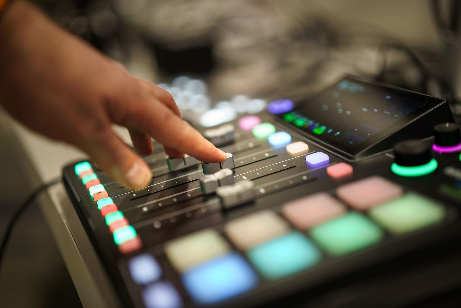 A hand adjusting faders on a professional audio mixer in a recording studio.