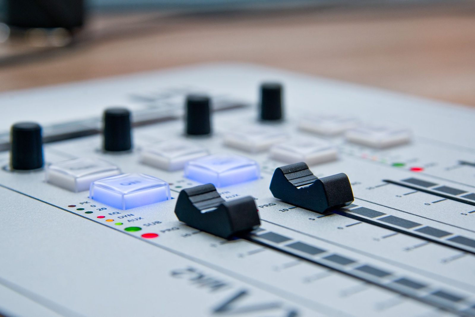 Detailed view of a professional sound mixer with glowing controls and sliders for audio production.