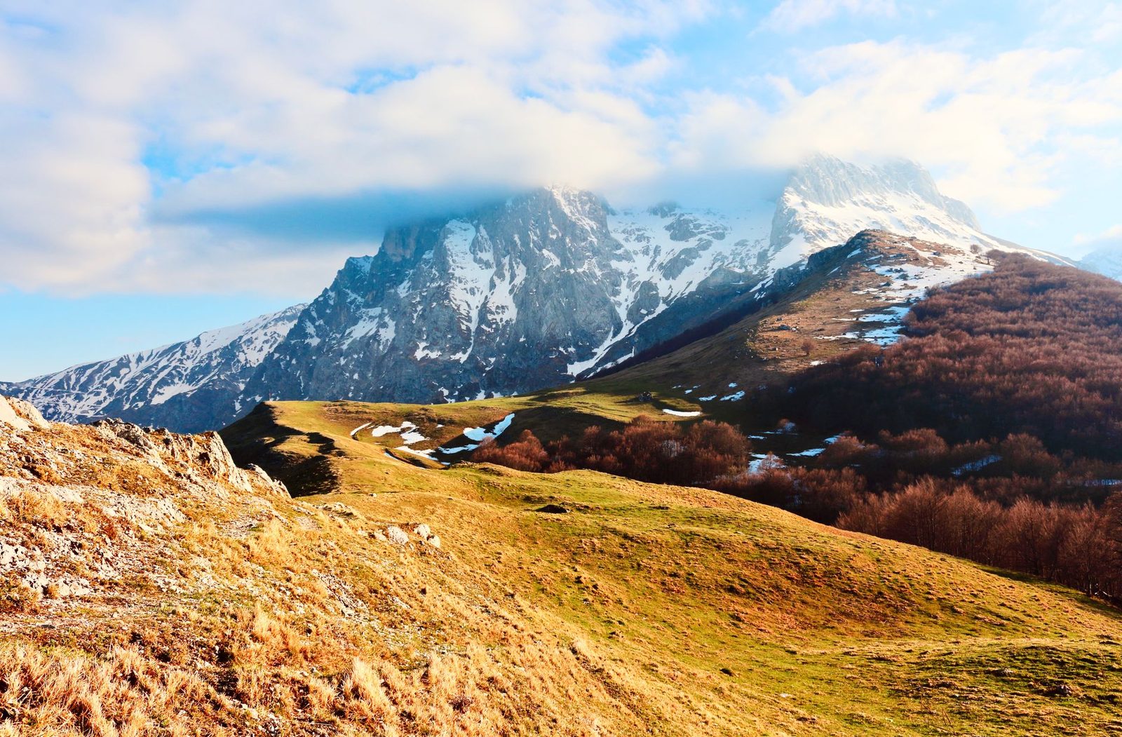 Breathtaking view of snow-capped Gran Sasso peaks at Prati di Tivo in Abruzzo, Italy, under a bright blue sky.