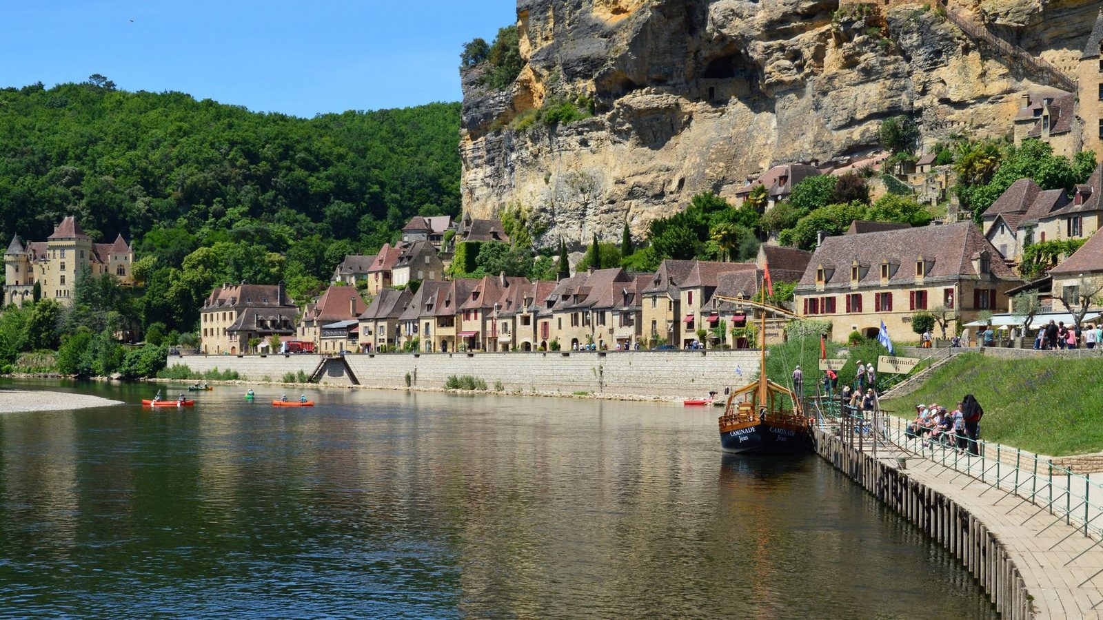 Picturesque riverside village in Dordogne, France with historic buildings and lush greenery.