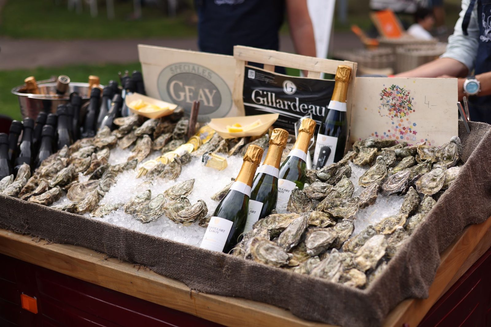 Elegant display of champagne bottles and fresh oysters at an outdoor market, offering a luxurious dining experience.