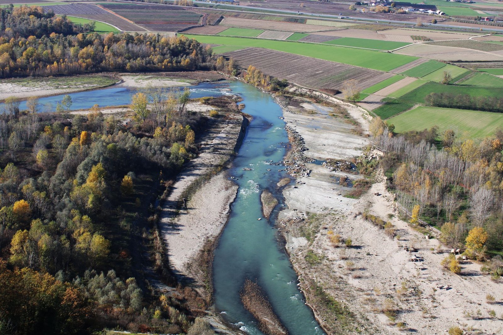 Aerial view of river and fields in Barbaresco, Piemonte during autumn, showcasing vibrant nature.