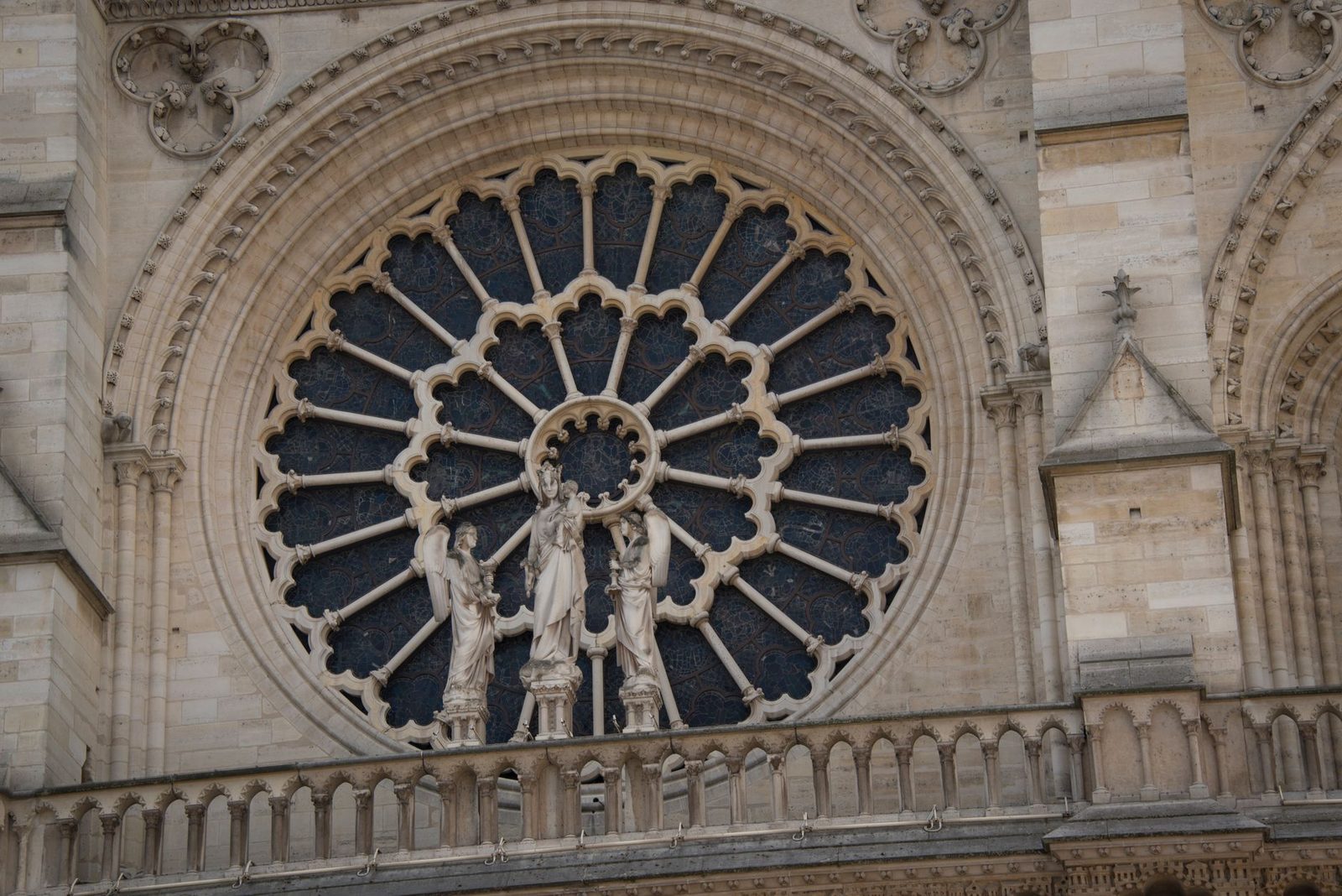 Detailed view of a gothic rose window with sculptures on a cathedral facade.