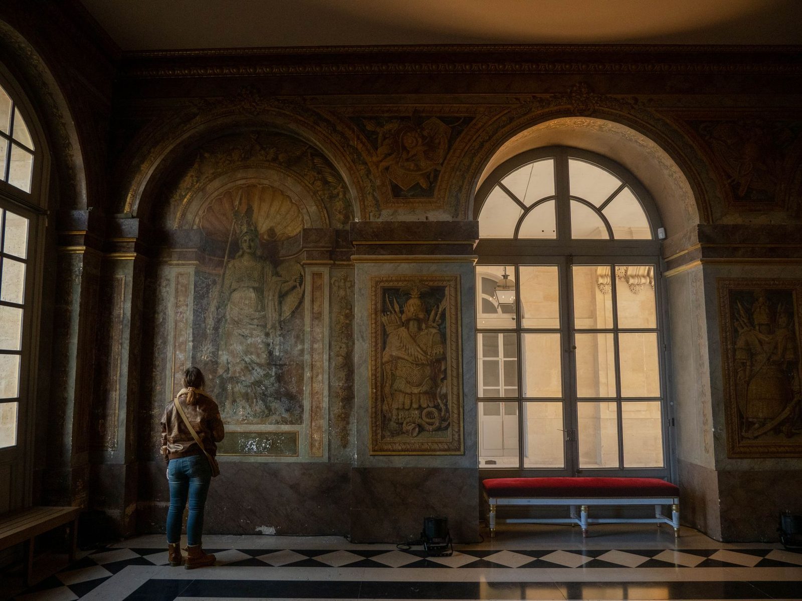 A person admires frescoes in the stunning interior of Versailles Palace, France.