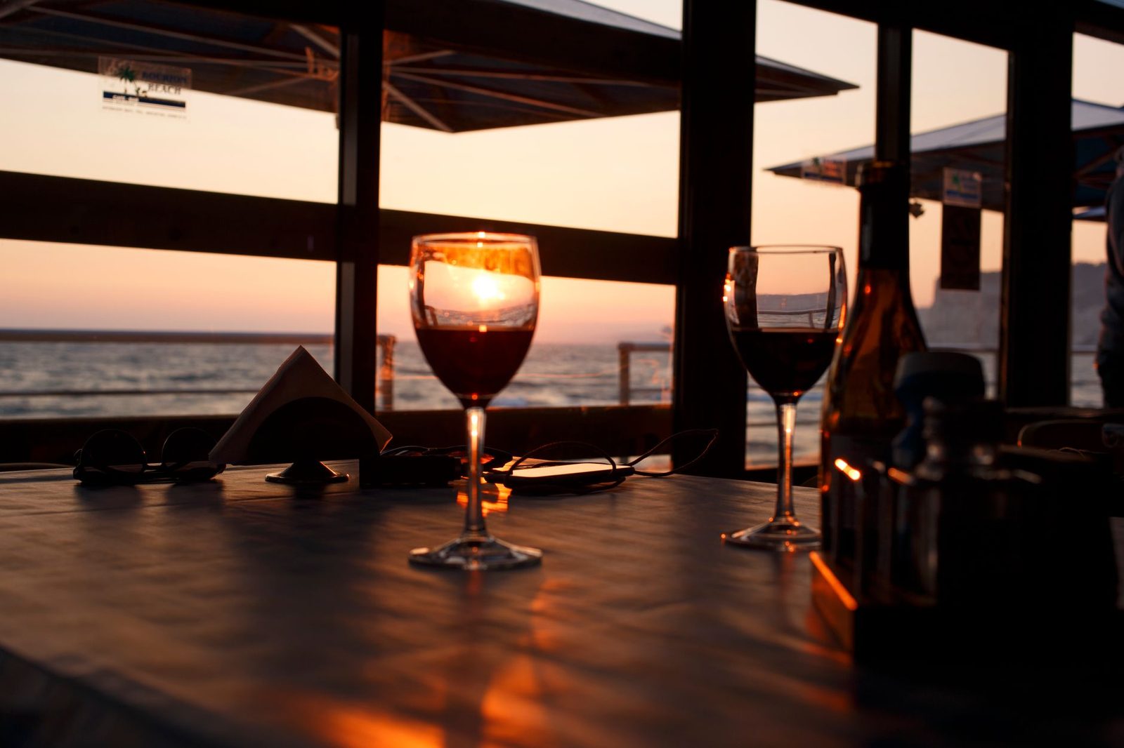 Elegant setting with wine glasses at sunset by the sea for a romantic atmosphere.