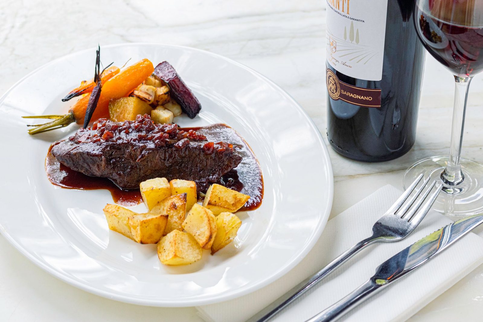 Elegant gourmet meat dish served with vegetables and a glass of red wine.