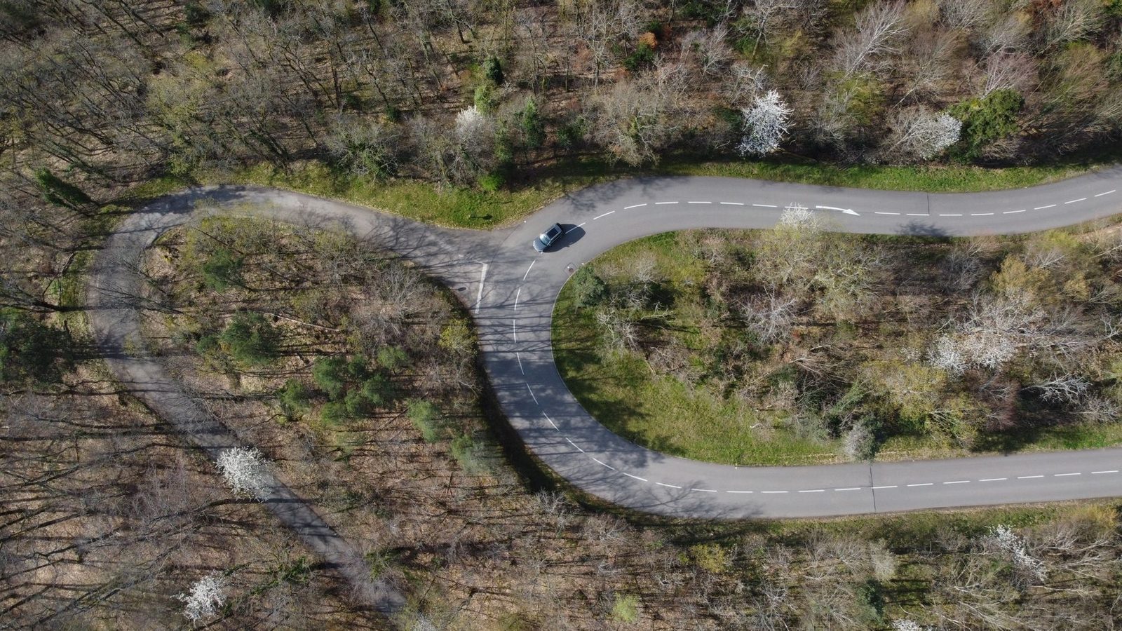 Drone shot capturing a curvy road through a forest in Kintzheim, Grand Est, France.