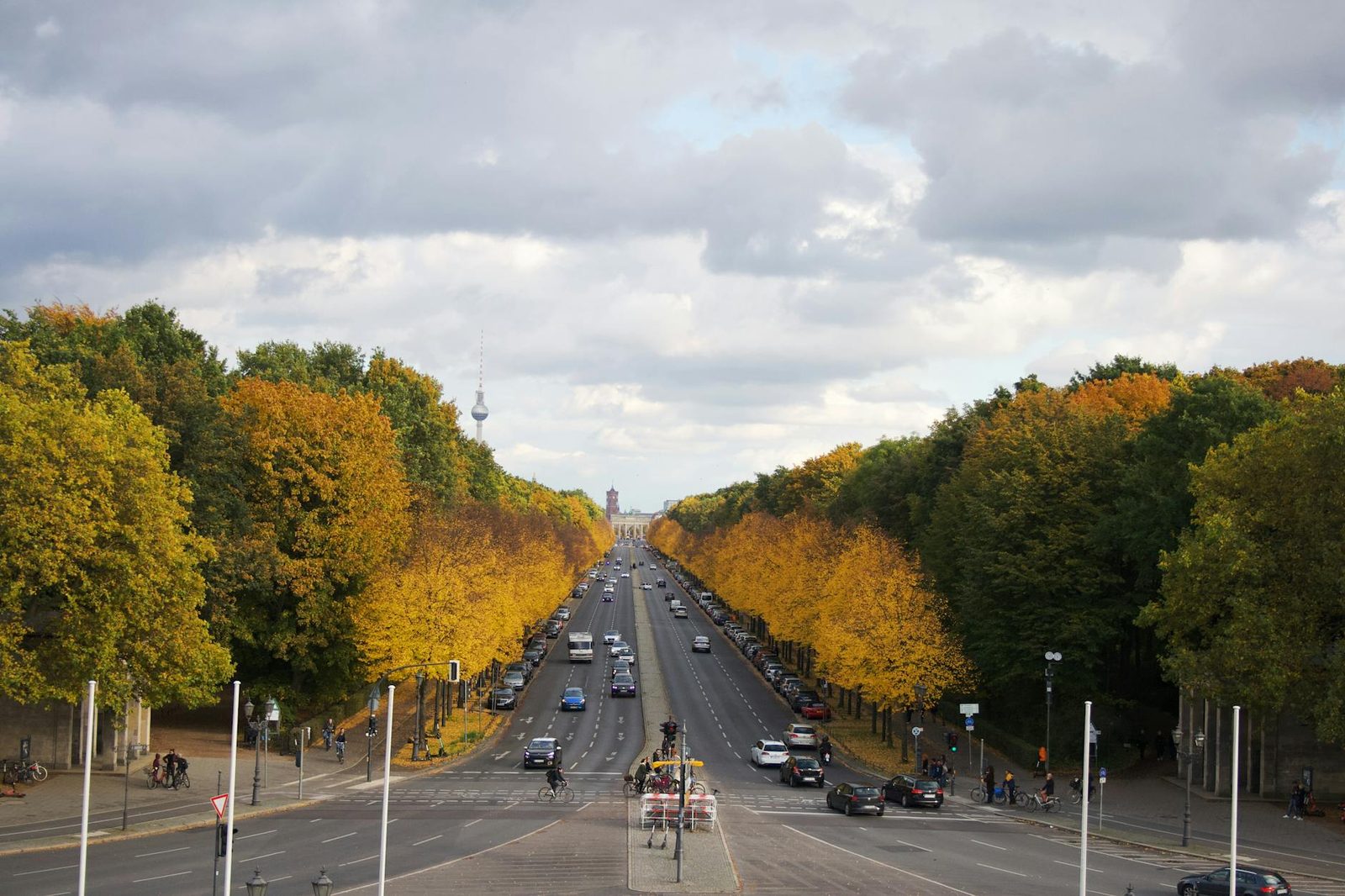 A vibrant autumn avenue with fall colors in Berlin's Tiergarten, showcasing city traffic and scenic trees.