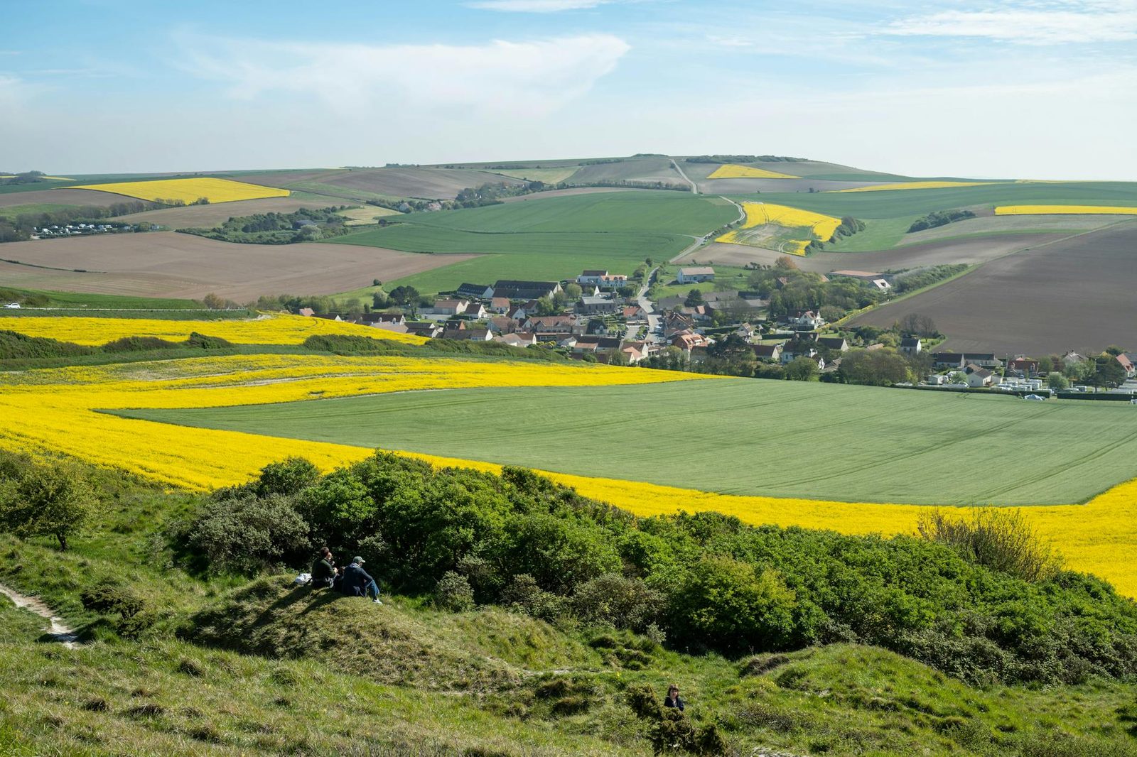 Lush green and yellow fields surround the quaint village of Escalles, France.