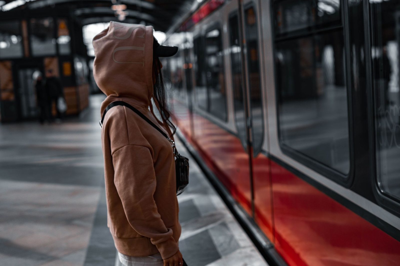 Individual in brown hoodie waiting for a train in Berlin station.