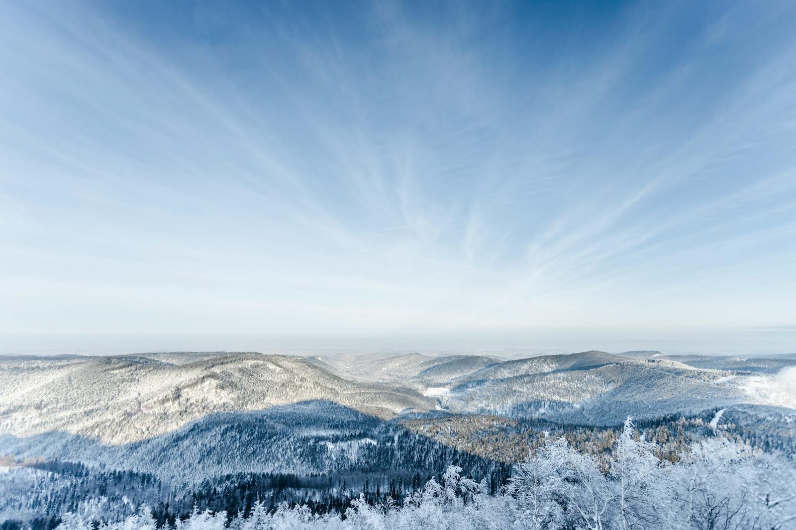 Aerial view of snow-covered mountains under a blue sky in Grandfontaine, France.